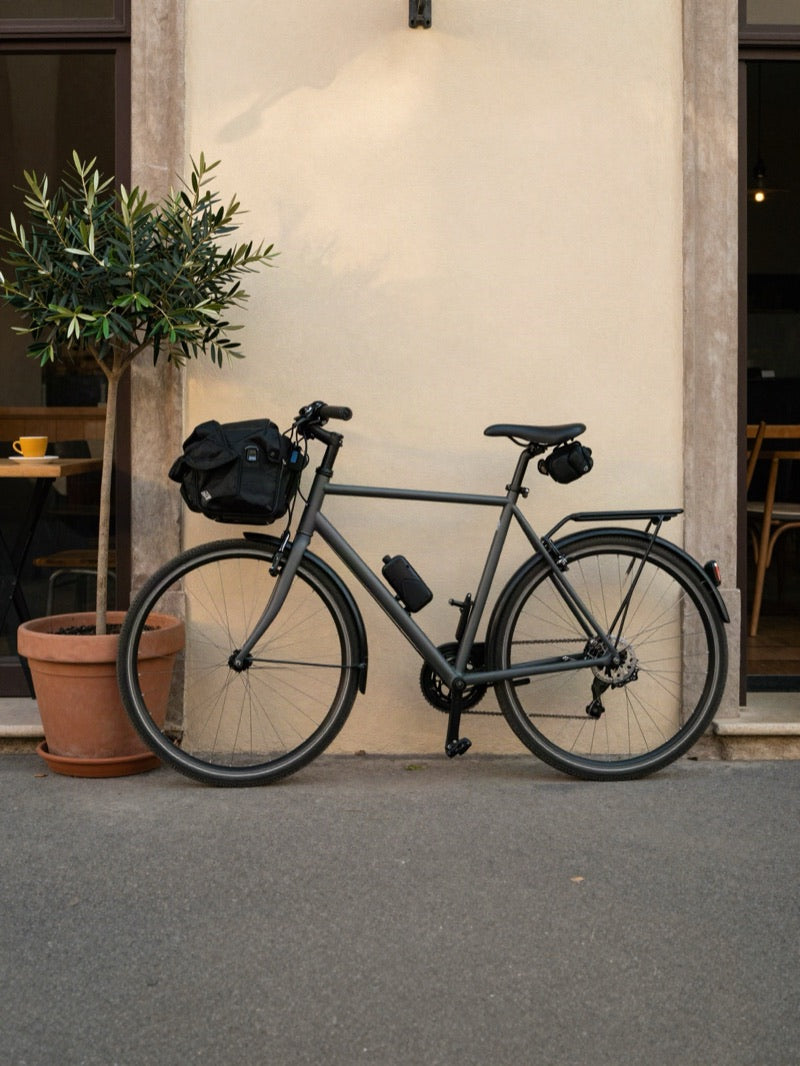 City bike with bags leaning on a cream wall outside a café